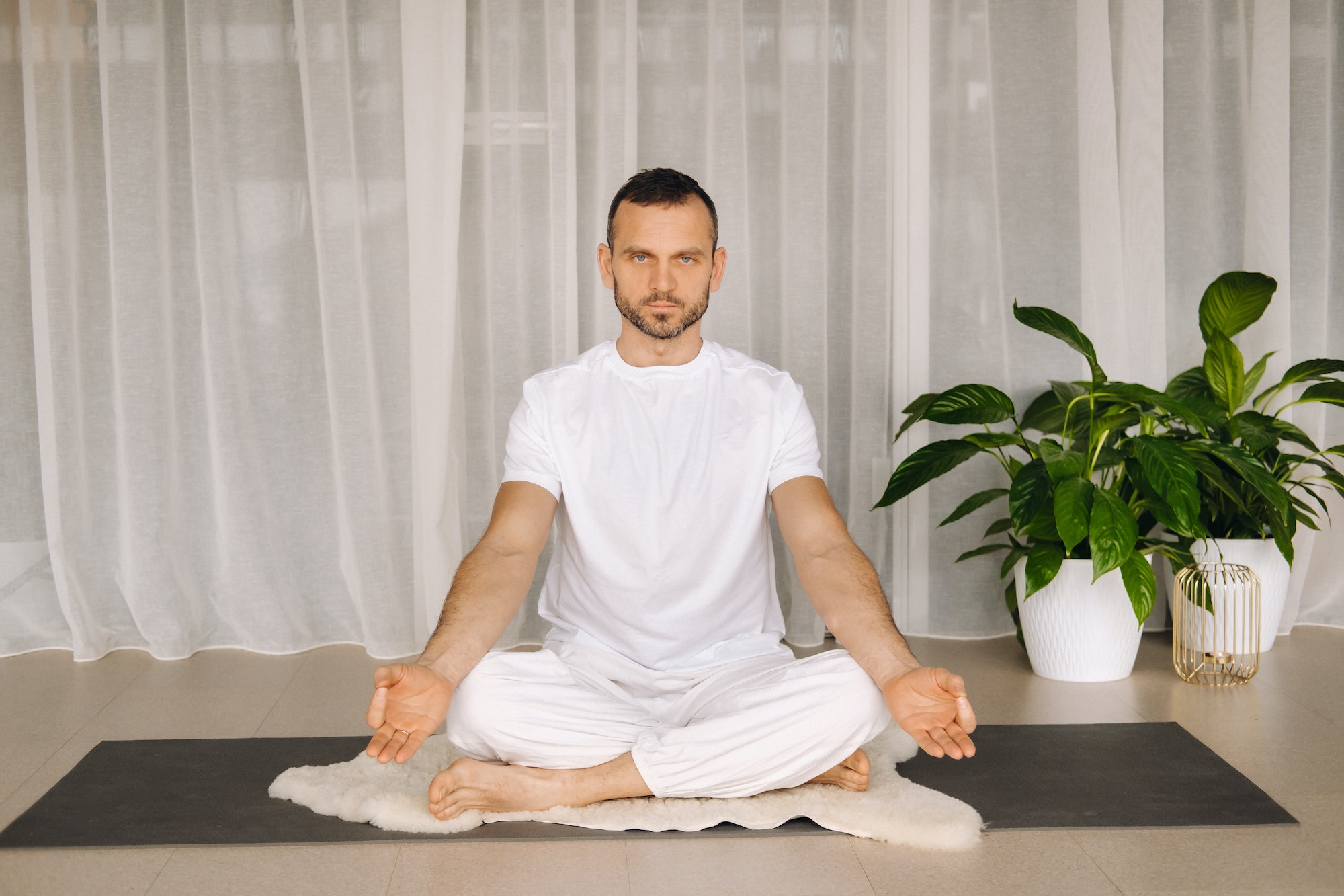 a man in white sportswear is doing yoga with a fitness room. the concept of a healthy lifestyle