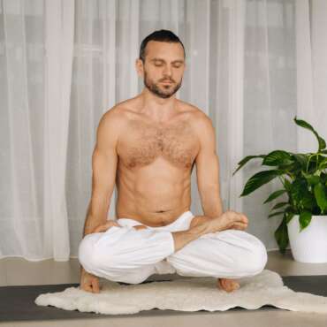 a man with a bare torso does yoga in a fitness room. the concept of a healthy lifestyle