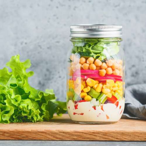 Single jar with layering vegan salad for healthy lunch. The concept of fitness and vegetarian food.